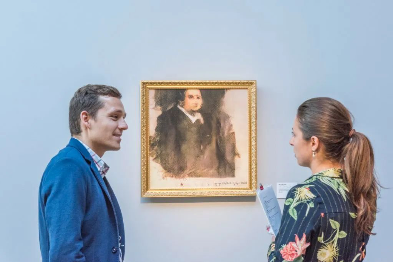 Two people looking at a painting on a wall

Description automatically generated